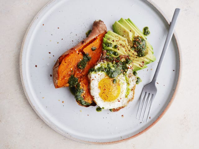 loaded baked sweet potatoes with avocado, pesto, and fried eggs horizontal