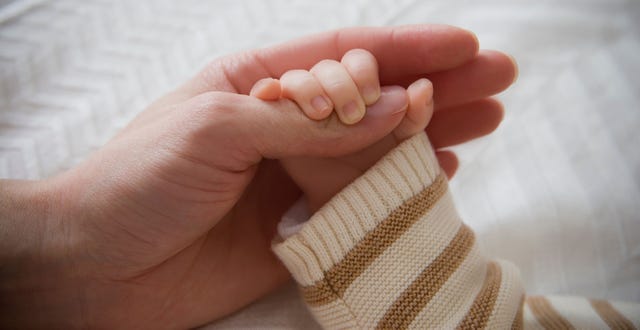 baby and mom holding hands
