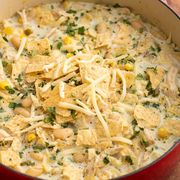 pot of white chicken chili filled with beans, corn, pulled chicken and topped with cheese and crushed tortilla chips