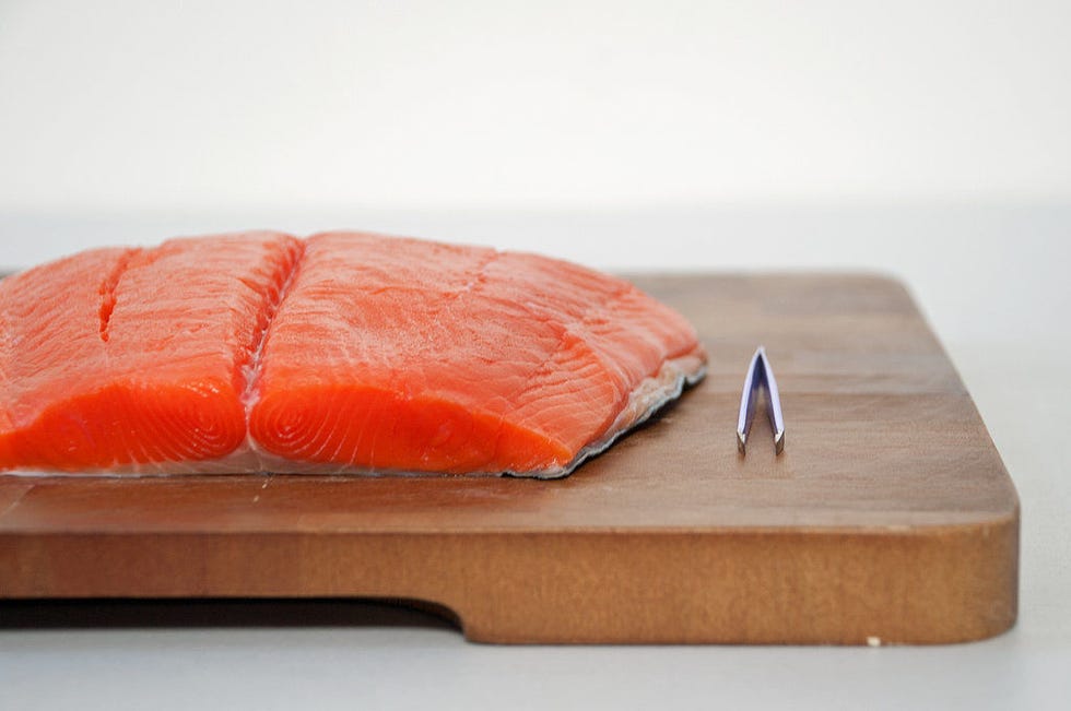 <p>Inspect the salmon both visually and with your fingertips to find any pin bones — small, flexible bones that are sometimes overlooked by the fishmonger — and remove them with a pair of (clean) tweezers.</p>