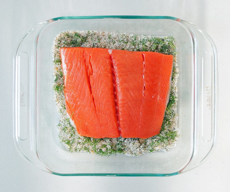 <p>Spread about half of the curing mixture on the bottom of the dish that will house the salmon while it cures. Nestle the salmon on top, skin-side down.</p>