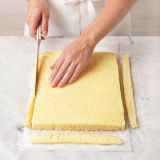 <p>Using a serrated knife, trim away the crisp edges from all sides of the cake.</p>