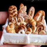 <b>The Artist:</b> Eve, <a href="http://afterdarkminiatues.blogspot.com/" target="_blank">After Dark Miniatures</a><br /><br />

Warning: This petite basket will make carb lovers drool. Eve's passion for making miniatures took hold of her when she a young girl, but it wasn't until many years later that she took a stab at creating mini food. Now she has a collection of miniatures that reflect a wide range of foods you might find on someone's kitchen table, from cakes and cookies, to baskets of fruit, and even meat plates.