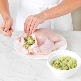 <p>Insert the herb stuffing into the body cavity, being careful not to tear the skin. Avoid overfilling the cavity because the stuffing will expand during cooking due to the absorption of the juices from the chicken. Never stuff the cavity in advance because this will increase the risk of bacteria growth.</p>