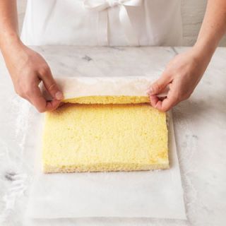 <p>With no filling, and using the sugared baking paper as a guide, gently roll the warm cake loosely. You do this so that once you've spread it with jam, it will roll up easily.</p>