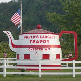 <p><strong>Location</strong>: Chester, West Virginia</p>
<p><strong>Address</strong>: Across the street from 751 Carolina Ave, Chester, WV 26034</p>
<p>Chester's giant teapot is self-proclaimed the largest in the world. The structure is 14 feet in diameter and approximately 14 feet tall. It was built in 1938 by converting an oversized root beer keg, once used as an ad for a Hire's Root Beer promotion. William Devon bought the barrel and converted it into a teapot but covering it with tin and placing a large glass ball on top for the knob of the lid. A concession and souvenir stand were set up inside the teapot next to Devon's pottery outlet store. While the souvenirs have moved to the gas station across the street, the teapot was restored in the 1990s, making it a prime road trip stop.</p>