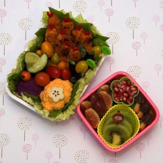 Vegetarian buffalo wings spice up a colorful bento alongside purple and yellow cauliflower and tiny multihued tomatoes.