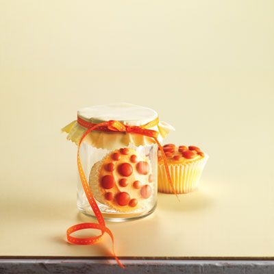 <p>Color butter cream orange. Spread the top of each cake evenly with the butter cream. Position orange Smarties and orange mini M&M's on each cake.</p>