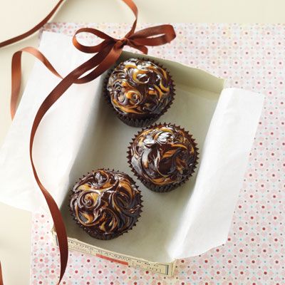 <p>Spread the top of each cake with a fairly thick layer of dark chocolate ganache. Dollop about six small dots of caramel sauce on the ganache. Pull a skewer back and forth through the caramel for a marbled effect.</p>