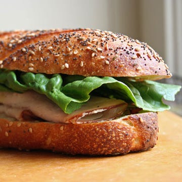 Packing sandwiches for the open road can be messy business — by the time lunch rolls around, the sandwich bread can be squishy and saturated with tomato juice. Once you start eating the sandwich, more of it can end up in your lap than in your mouth. Let's toss those subpar roadie sandwiches aside and start making perfect travel sandwiches instead. All you need are a baguette, your favorite condiment, an avocado, deli meat, cheese, and a large lettuce leaf. Learn the magic behind the one-handed, spill-free sandwich that's easy to eat while you're on the open road.