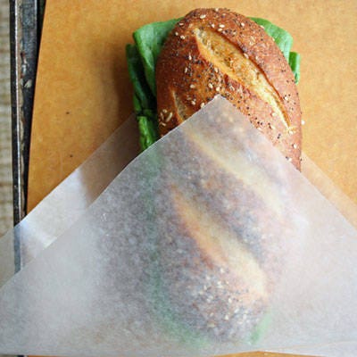 <b>Wrap the Sandwich</b>

To keep your hands mess free on the road, place the sandwich in a wax paper "koozie." Start with a square piece of wax paper. Fold it in half to create a triangle. Slip the sandwich in between the paper until the sandwich bottom hits the fold of the paper, and the tops of the triangle rest in the center of the sandwich. Fold the right side of the paper tightly across the sandwich, and repeat on the left side. To save the sandwich for later, wrap it tightly in clingy plastic wrap or in a large plastic baggie.