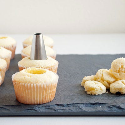 Insert the base of a large pastry tip (I use <a href="http://www.amazon.com/gp/product/B00004S1CN/ref=as_li_ss_tl?ie=UTF8&camp=1789&creative=390957&creativeASIN=B00004S1CN&linkCode=as2&tag=popsho-20" target="_blank">Ateco's #800</a>) into the center of the cupcake about 1/4-inch deep (1/2-inch deep if filling and then frosting), and twist until the cake center twists alongside the tip; pull directly up to remove the center. Reserve the cake centers if your cupcakes will be frosted (rather than just filled), otherwise discard or eat the centers.