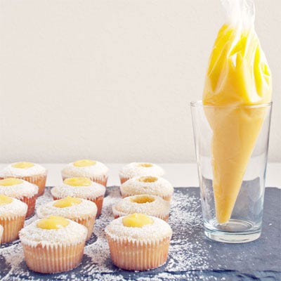 <p>Securely twist the pastry bag until it's taut; snip off the tip of the bag and deposit the filling in the wells of the cupcakes by twisting the top of the bag to apply pressure and pipe out the filling.</p>
<p>If frosting the cupcakes after filling, leave about 1/4-inch headroom in each cupcake. Slice off all but the top 1/4 inch of the reserved cupcake centers to make a thinner disc, and then nestle them on top of the filled centers, pressing them in until they're roughly flush with the cupcake tops. Proceed with piping frosting.</p>
