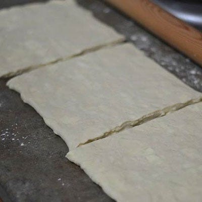<p>Make sure to seal the edges so that the butter doesn't escape from the sides of the dough.</p>

<p>To lock in the butter, roll the dough out on a lightly floured surface. The dough should be longer than it is wide. Fold the right side toward the middle and then the left side over on top of the right side, like you are folding a letter. This creates the dough layers. Repeat this process two more times and remember to chill thoroughly in between. Roll the dough out again, making sure that your corners are squared off, and cut dough into thirds. We chose to stack these pieces of dough to give the cronut height and lots of flaky and buttery layers. Roll the dough out one last time. Make it large enough to cut out one dozen cronuts.</p>
