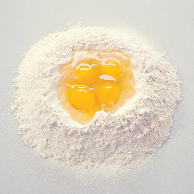 <p>Make a well in the mound of flour that's large enough to accommodate four large eggs. Crack the eggs into the well and then begin to incorporate them into the flour with clean fingertips, pulling in the flour bit by bit. Keep at it until the eggs are evenly distributed and a shaggy dough forms. </p>
