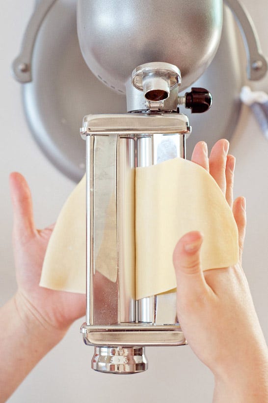 <p>Starting on the lowest setting (1 on a <a href="http://www.amazon.com/gp/product/B00004SGFS" target="_blank">KitchenAid pasta roller attachment</a>), pass the dough through the machine. Fold the sheet of dough in half lengthwise, pressing it firmly together, then pass it through on the lowest setting three to four more times, or until the dough is smooth and silky. Continue to pass the dough through the pasta roller, adjusting it one notch at a time (do not fold the dough onto itself) until it reaches the desired thinness. If the sheet of pasta becomes too long and unmanageable to work with, cut it into two smaller portions and roll them out one at a time. </p>
<p>Repeat with the remaining pieces of dough, storing the rolled-out sheets of pasta between clean dish towels.</p>