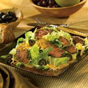 Here's a hearty salad that's sure to satisfy...it's like an upscale taco salad made with grilled marinated skirt steak served over lettuce with cheese, tomatoes, and olives.