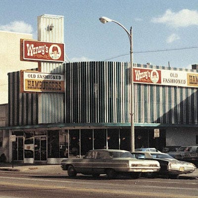 Wendy's <p><b>Year Opened:</b> 1969</p>
<p><b>First Location:</b> Columbus, OH</p>
<p><b>Bite of History:</b> In the late 1950s, Dave Thomas and business partner Phil Clauss had the good fortune of working with the legendary founder of Kentucky Fried Chicken, Colonel Harland Sanders. In 1962, Thomas was charged with turning around four underperforming KFC restaurants. If he succeeded, the high school dropout would become a millionaire. Six years later, he fulfilled his obligation and was hired as a regional director. A year later, Thomas left KFC to pursue his own restaurant concept. On November 15, 1969, inside an old car dealership, Thomas opened Wendy's Old Fashioned Hamburgers (named after his 8-year-old daughter, Melinda Lou, nicknamed "Wendy" by her siblings), selling made-to-order burgers for just 55 cents. Today, there are more than 6,000 Wendy's worldwide.</p>