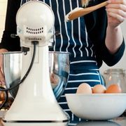 person holding a wooden spoon in front of a stand mixer