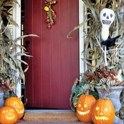 Make your front door season-appropriate, framing it with dried corn husks and a garland of oak leaves. Ghostly bottle-gourd scarecrows were painted white, with features added in black felt tip, and then speared on sticks and "planted" in Styrofoam blocks inside urns.