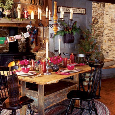 <p>Cranberry-red china and bouquets of deep-pink roses in pewter vases dress a late-1700s Pennsylvania hutch table. A collection of Santa figurines is displayed on the mantel among miniature pine trees and cedar sprigs. Christmas cards are strung across the fireplace beside handmade boiled-wool stockings. A garland of dried berries dyed red drapes around a corner tree and fills a basket on the wall.</p>