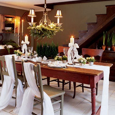 <p>Balsam boughs, poinsettias, miniature cypress topiaries, candles, and gauzy fabric and ribbons give the dining room a sophisticated holiday look.</p>