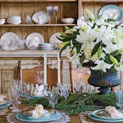 <p>An abundant white floral arrangement surrounded by pine branches serves as the focal point of this simple setting.</p>