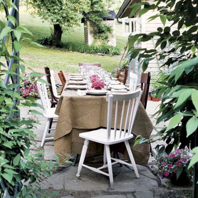 Set up a long table on a patio or cover two smaller tables with a tablecloth for a relaxed gathering. Mismatched chairs add to the laid-back feel. Add a touch of color with small bouquets running down the center of the table.