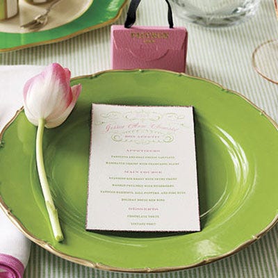 A spring green plate garnished with a single rose-tinged tulip sets a cheery backdrop for an alfresco meal. A mini pink handbag filled with chocolates and an individual menu makes guests feel special.