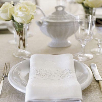 An all-white table setting gives a feeling of luxury. Use embroidered cloth napkins, white dishes, and white roses in glass vases.