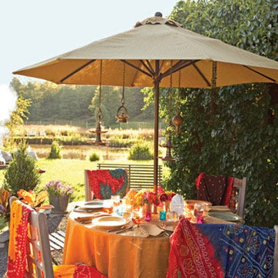 Set the scene for an exotic outdoor soiree. A giant umbrella shields party guests from the blazing afternoon sun, and hanging lanterns will illuminate the table come nightfall. Mix citronella candles with other colorful tea lights to keep away pests, and offer diners light cotton shawls to ward off a chill in the evening.
