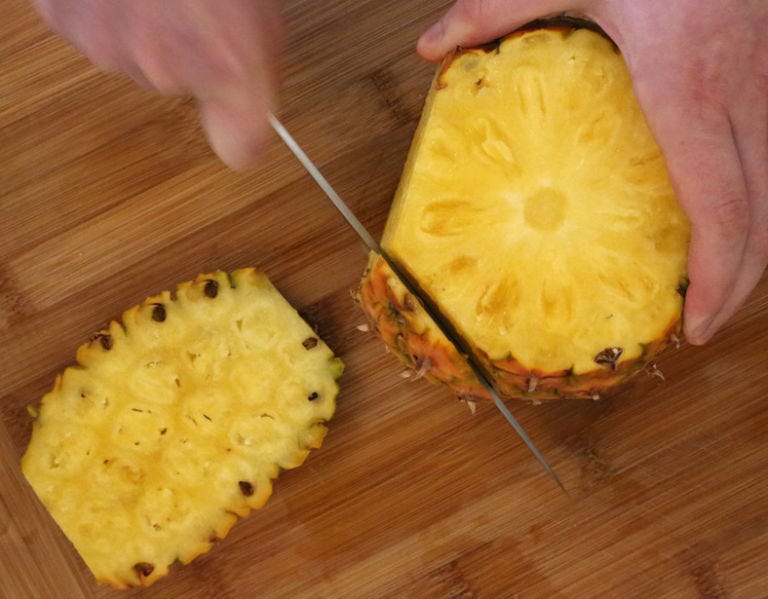 <p>Run the knife down the length of the pineapple. You want to cut in deep enough so that all the prickly brown bits are cut off. I make about seven cuts, but you could do more or less, depending on how much you chop off, and how big your pineapple is.</p>