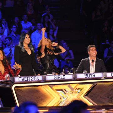 r to l, simon cowell, paulina rubio, demi lovato, and kelly rowland behind the x factor judging desk, with rubio punching the air