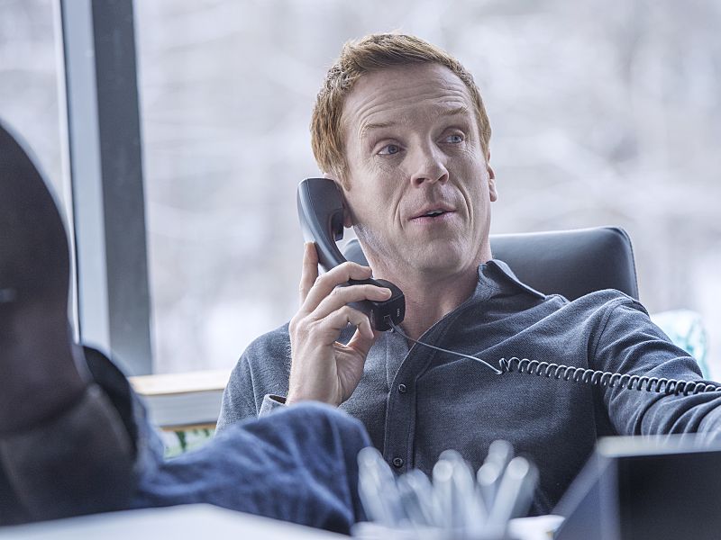 billions damian lewis talks on the phone with his feet on the desk
