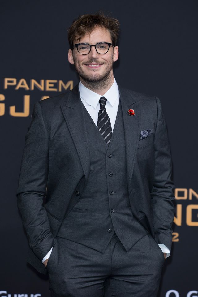 sam claflin smiling at the camera and wearing glasses