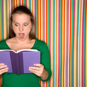 Woman reading a book and looking shocked