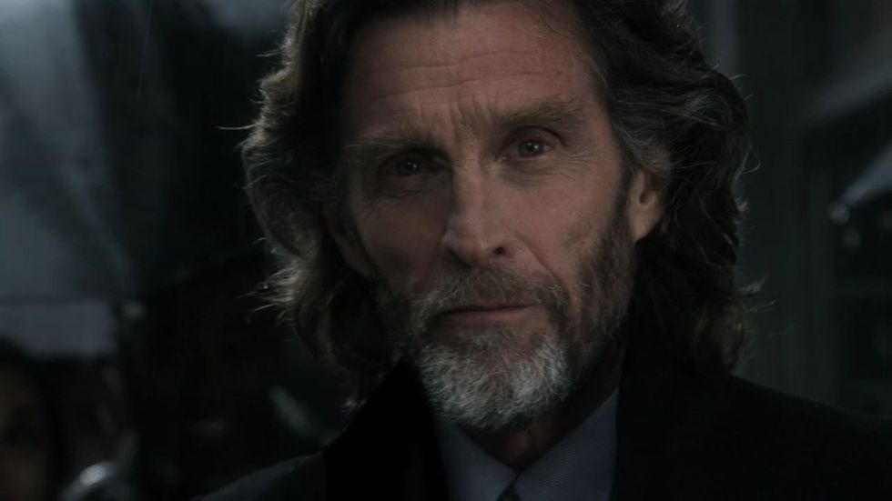 Schauspieler John Glover in der Rolle des Lionel Luthor in Smallville. Der Schauspieler hat langes schulterlanges Haar und starrt in die Kamera