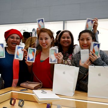 Customers hold up the iPhone X in an Apple store - November 2017