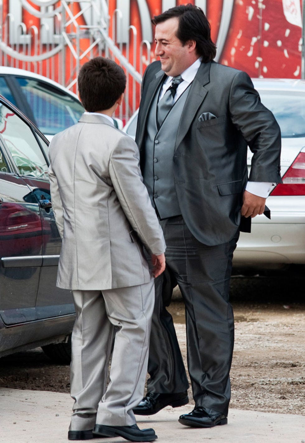 Clothing, Coat, Trousers, Automotive design, Suit trousers, Shirt, Suit, Standing, Outerwear, Vehicle door, 
