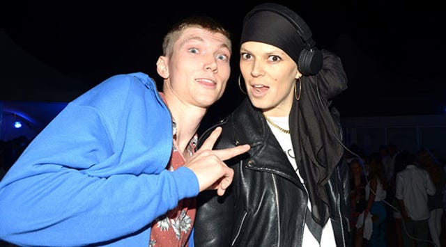 Cap, Jacket, Leather jacket, Leather, Flash photography, Gesture, Thumb, Scarf, Body jewelry, Top, 