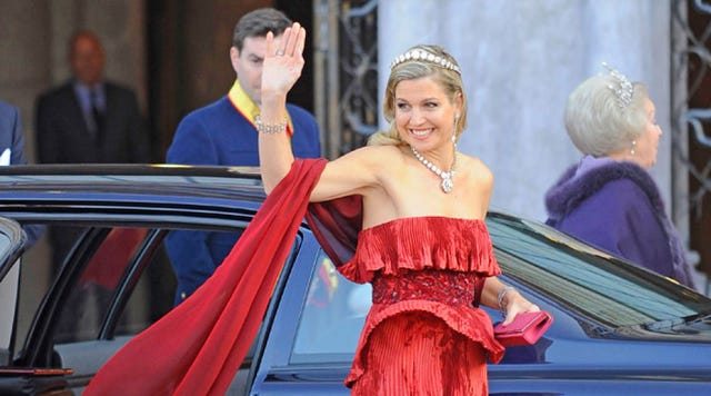 Dress, Facial expression, Coat, Fashion accessory, Suit, Formal wear, Strapless dress, Gown, Headpiece, Hair accessory, 