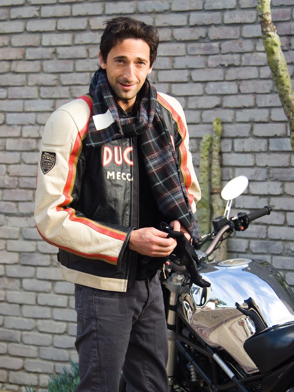 Motorcycle, Fender, Motorcycle accessories, Automotive lighting, Jacket, Bag, Fuel tank, Facial hair, Street fashion, Brick, 