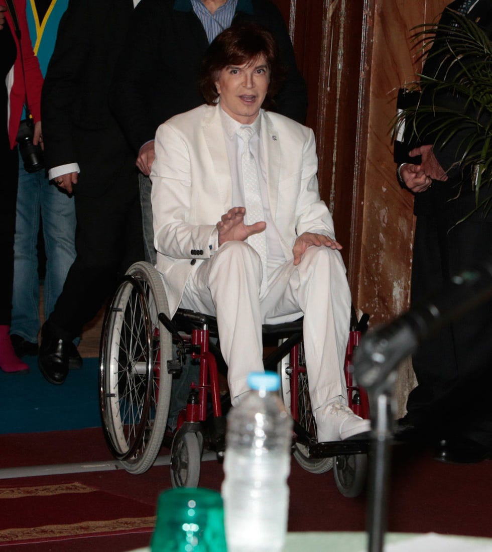 Leg, Wheelchair, Plastic bottle, Suit trousers, Bottle, Curtain, Lap, Bottle cap, Water bottle, 