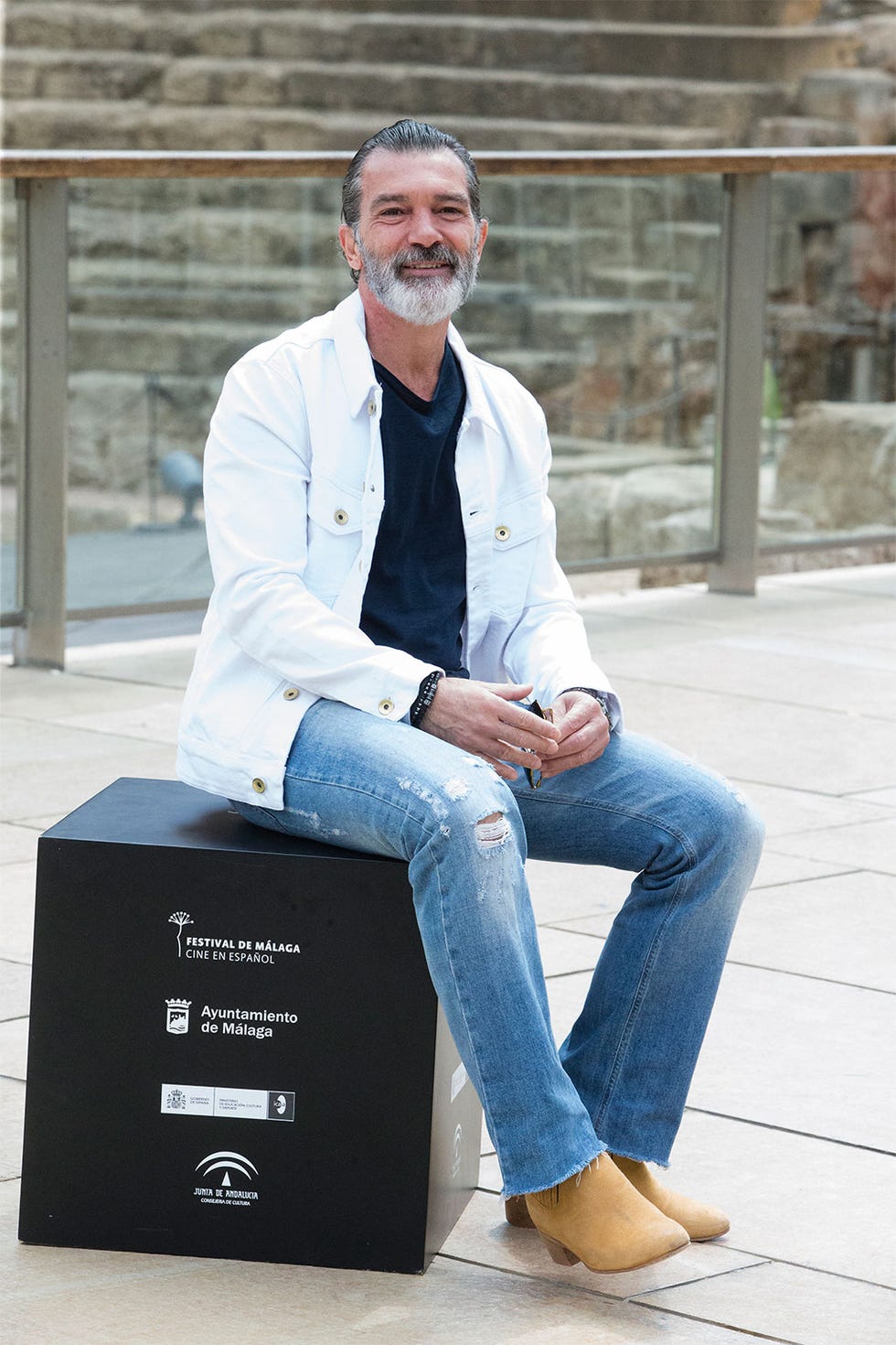 Sitting, Denim, Jeans, Footwear, Dress shirt, Suit, White-collar worker, Blazer, Shoe, Outerwear, 