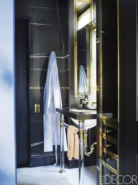 A sink from Urban Archaeology, with fittings by Waterworks, in Alexander's bath; the cabinets are black glass with brass trim, the walls are clad in Saint Laurent marble, and the flooring is limestone.