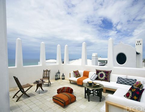 On the terrace, which overlooks the Gulf of Mexico, the bone-inlaid folding chairs, side table, and brass-topped cocktail table are Moroccan; the sofa pillows are covered in antique suzanis and the floor pillows in vintage kilims.