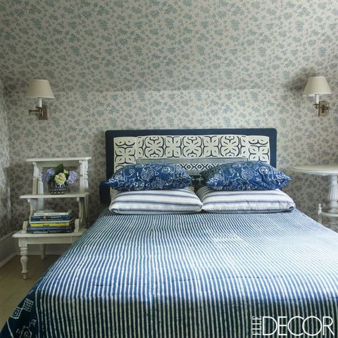 The bed's headboard, pillow shams and cover are made from Indian batiks and the walls are covered in blue and white floral fabric