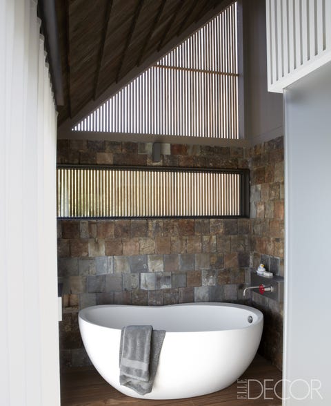 The tub in the master bath is by Waterworks, with fittings by Boffi; the walls are sheathed in reclaimed slate tiles, and the flooring is mahogany.