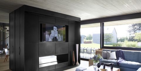 The family room's custom-made sectional sofa is upholstered in a fabric by BDDW, the cocktail table is by Etel Carmona for Espasso, the rug is by Fort Street Studio, and the cabinetry is made of blackened perforated steel.