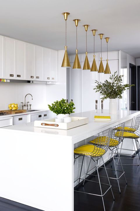 The kitchen island and counters are topped with a Caesarstone surface, the Bertoia barstools are by Knoll, and the 1950s pendants are Italian; the refrigerator is by Thermador, and the sink by Elkay has Rohl fittings.